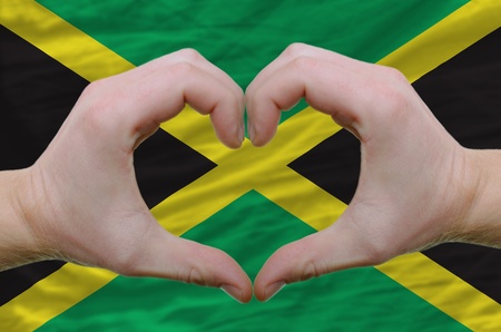 Gesture made by hands showing symbol of heart and love over jamaica flagの写真素材