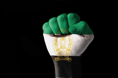 Low key picture of a fist painted in colors of aghanistan flagの写真素材