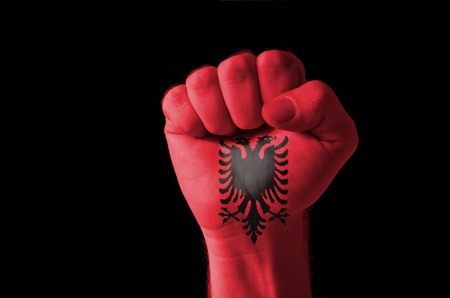Low key picture of a fist painted in colors of albania flagの写真素材