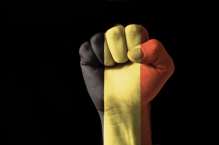 Low key picture of a fist painted in colors of belgium flagの写真素材