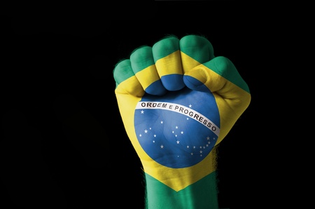 Low key picture of a fist painted in colors of brazil flagの写真素材