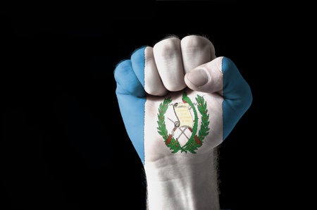 Low key picture of a fist painted in colors of guatemala flagの写真素材