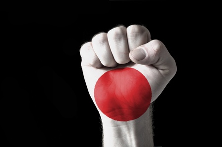 Low key picture of a fist painted in colors of japan flagの写真素材