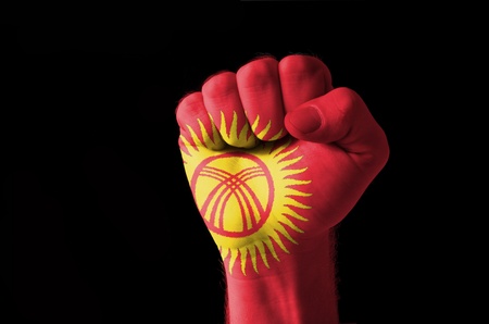 Low key picture of a fist painted in colors of kyrghyzstan flagの写真素材