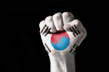 Low key picture of a fist painted in colors of south korea flagの写真素材