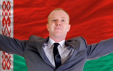 joyful investor spreading arms after good business investment in belarus, in front of flagの写真素材