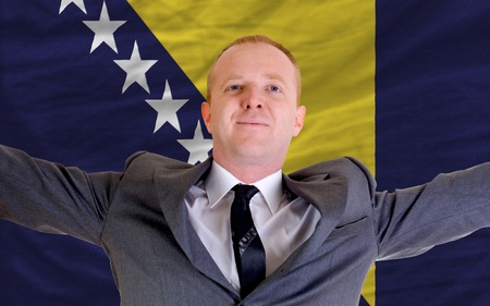 joyful investor spreading arms after good business investment in bosnia herzegovina, in front of flagの写真素材