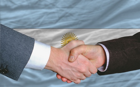 two businessmen shaking hands after good business investment  agreement in argentina, in front of flagの写真素材