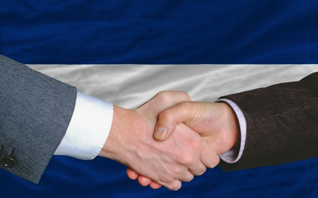 two businessmen shaking hands after good business investment  agreement in nicaragua, in front of flagの写真素材