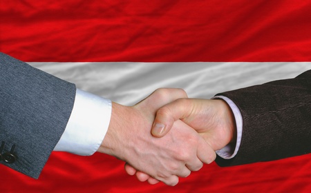 businessmen handshake after good deal in front of austria flagの写真素材