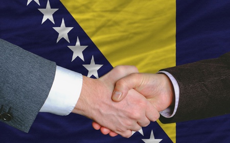 businessmen handshake after good deal in front of bosnia herzegovina flagの写真素材