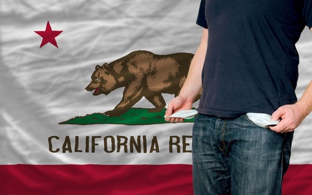 poor man showing empty pockets in front of california flagの写真素材