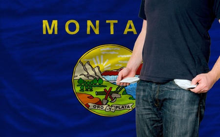 poor man showing empty pockets in front of american state of montana flagの写真素材