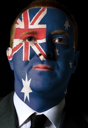 High key portrait of a serious businessman or politician whose face is painted in national colors of australia flagの写真素材