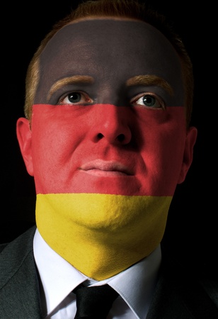High key portrait of a serious businessman or politician whose face is painted in national colors of germany flagの写真素材