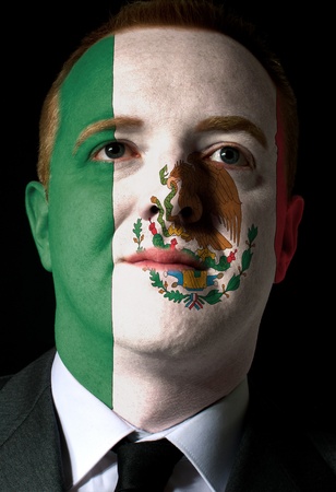 High key portrait of a serious businessman or politician whose face is painted in national colors of mexico flagの写真素材