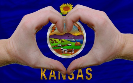 Gesture made by hands showing symbol of heart and love over us state flag of kansasの写真素材
