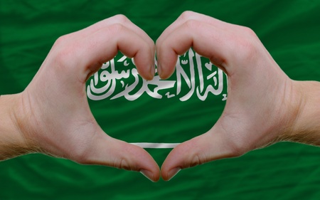 Gesture made by hands showing symbol of heart and love over flag of saudi arabiaの写真素材