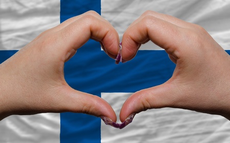 Gesture made by hands showing symbol of heart and love over national finland flagの写真素材