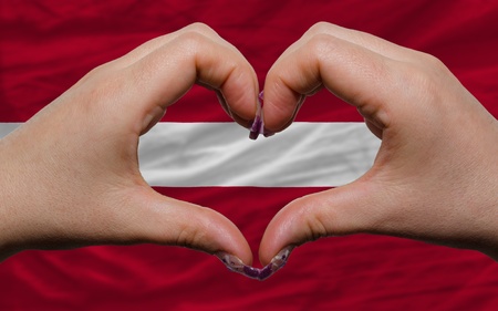 Gesture made by hands showing symbol of heart and love over national latvia flagの写真素材