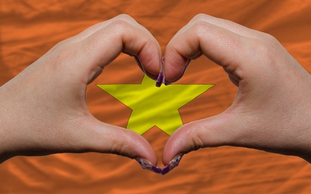 Gesture made by hands showing symbol of heart and love over national vietnam flagの写真素材