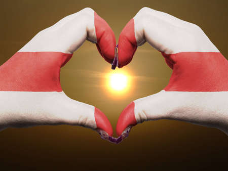 Gesture made by england flag colored hands showing symbol of heart and love during sunriseの写真素材