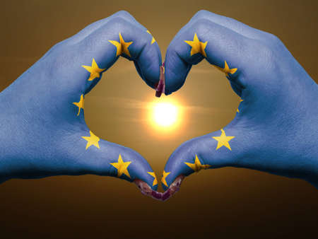 Gesture made by europe flag colored hands showing symbol of heart and love during sunriseの写真素材