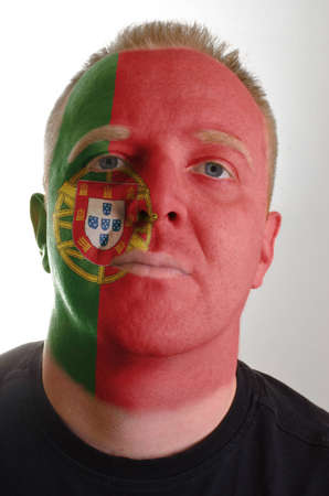 High key portrait of a serious man whose face is painted in national colors of portugalの写真素材