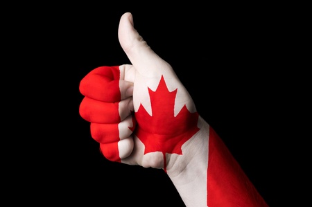 Hand with thumb up gesture in colored canada national flag as symbol of excellence, achievement, good, - for tourism and touristic advertising, positive political, cultural, social management of countryの写真素材