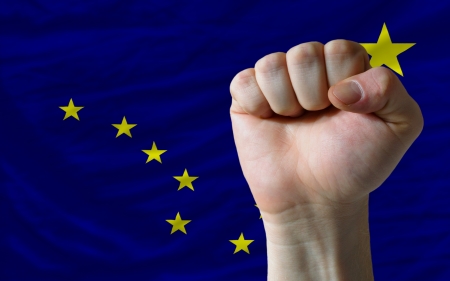 complete american state of alaska covers whole frame, waved, crunched and very natural looking. In front plan is clenched fist symbolizing determinationの写真素材