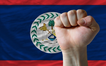 complete national flag of belize covers whole frame, waved, crunched and very natural looking. In front plan is clenched fist symbolizing determinationの写真素材