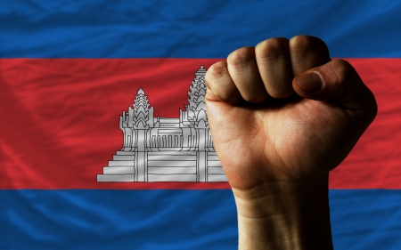 complete national flag of cambodia covers whole frame, waved, crunched and very natural looking. In front plan is clenched fist symbolizing determinationの写真素材