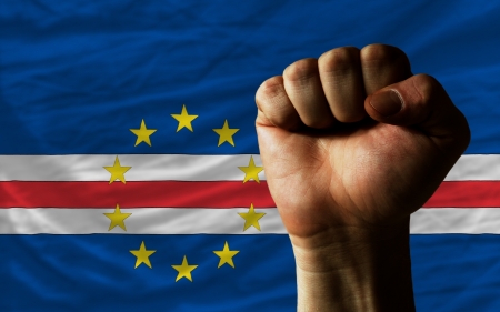 complete national flag of capeverde covers whole frame, waved, crunched and very natural looking. In front plan is clenched fist symbolizing determinationの写真素材