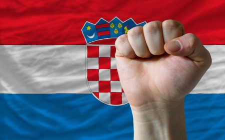 complete national flag of croatia covers whole frame, waved, crunched and very natural looking. In front plan is clenched fist symbolizing determinationの写真素材