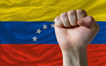 complete national flag of venezuela covers whole frame, waved, crunched and very natural looking. In front plan is clenched fist symbolizing determinationの写真素材