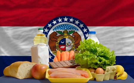 complete american state flag of missouri covers whole frame, waved, crunched and very natural looking. In front plan are fundamental food ingredients for consumers, symbolizing consumerism an human needsの写真素材