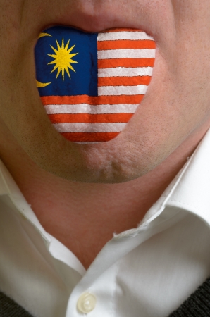 man wit open mouth spreading tongue colored in malaysia flag as symbol of values like teaching, learning, multilingual speaking of different languagesの写真素材