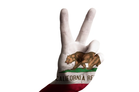 Hand with two finger up gesture in colored california state flag as symbol of winning, victorious, excellent, - for tourism and touristic advertising, positive political, cultural, social management of countryの写真素材