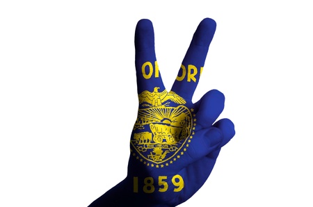 Hand with two finger up gesture in colored oregon american state flag as symbol of winning,...