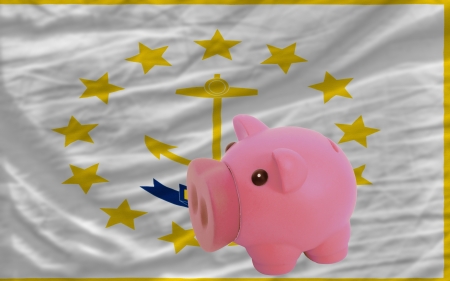 Piggy rich bank in front of flag of us state of rhode island symbolizing saving and accumulating funds as good financial habitの写真素材