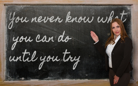 Successful, beautiful and confident woman showing You never know what you can do until you try on blackboardの写真素材