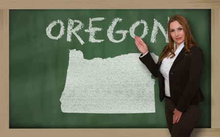 Successful, beautiful and confident young woman showing map of oregon on blackboard for presentation, marketing research and tourist advertisingの写真素材