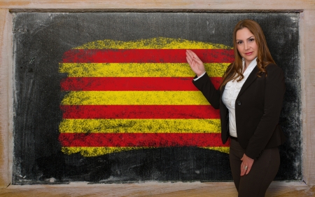 Successful, beautiful and confident woman showing flag of catalonia on blackboard for marketing research, presentation and tourist advertisingの写真素材