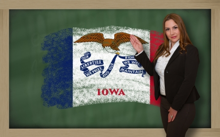 Successful, beautiful and confident woman showing flag of iowa on blackboard for marketing research, presentation and tourist advertisingの写真素材
