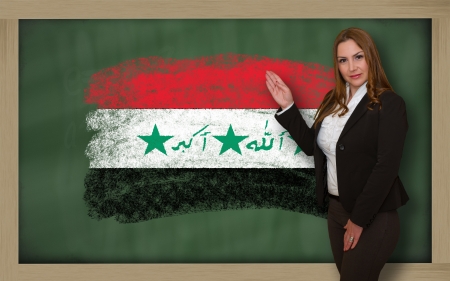 Successful, beautiful and confident woman showing flag of iraq on blackboard for marketing research, presentation and tourist advertisingの写真素材