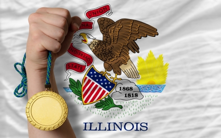 Winner holding gold medal for sport and flag of us state of illinoisの写真素材