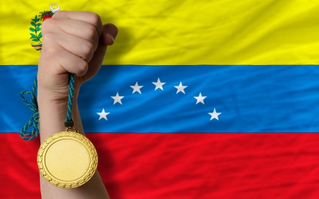 Winner holding gold medal for sport and national flag of venezuelaの写真素材