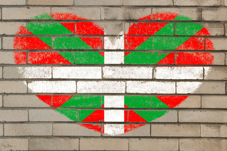heart shaped flag in colors of basque on brick wallの写真素材