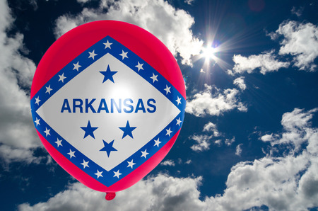 balloon in colors of arkansas flag flying on blue skyの写真素材