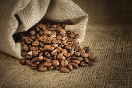 roasted coffee beans spill out of the bagの写真素材